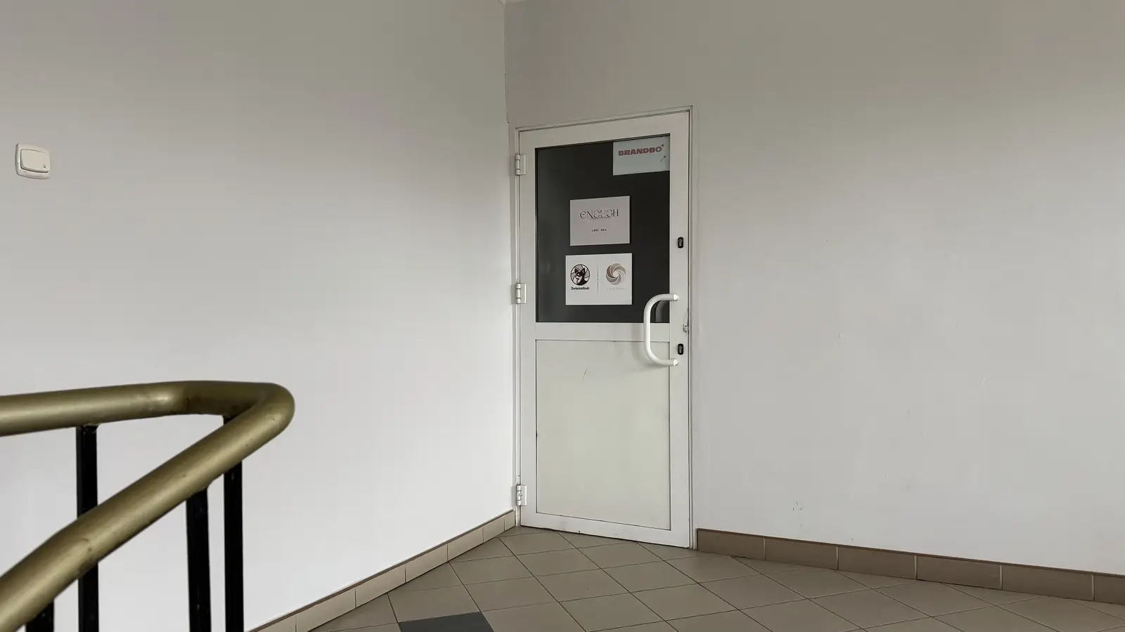 Wejdź przez białe drzwi naprzeciwko schodów.